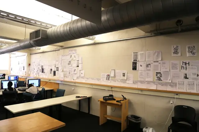 Fafalish installation: printed paper runs along a library wall above computer workstations