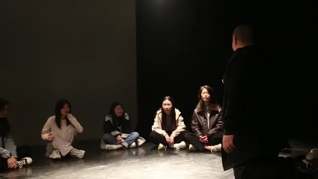 Participants sit in a circle on the floor of P4 Theater’s black-box space